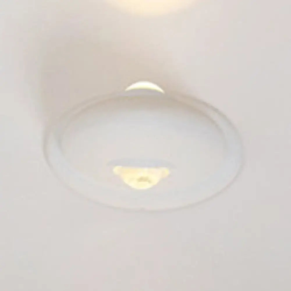 A sleek white and chrome modern triangle bedroom wall sconce lamp with a smooth rounded dome led bedroom wall light