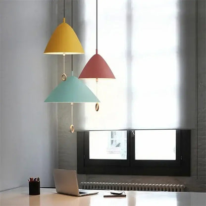 Three modern cone-shaped decorbites designer pendant lights in yellow red and teal with metallic hardware for dining room use