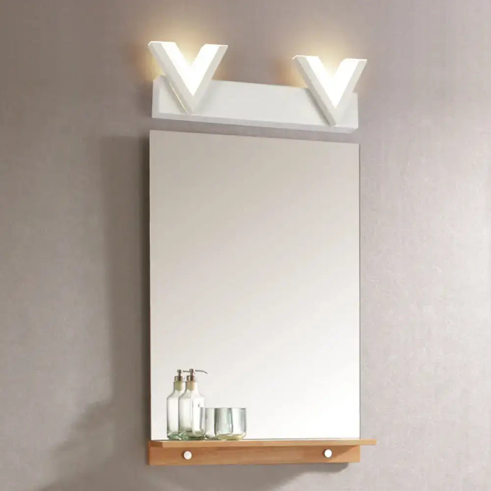 Modern v-shaped white led vanity light fixture with warm white illumination mounted above mirror and wooden shelf