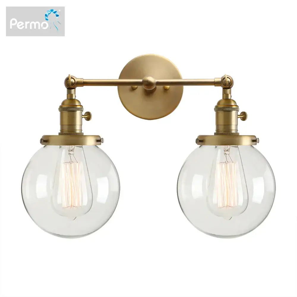 Modern vintage brass wall sconce with double ball heads clear glass globe shades and exposed filament bulbs for bedroom light