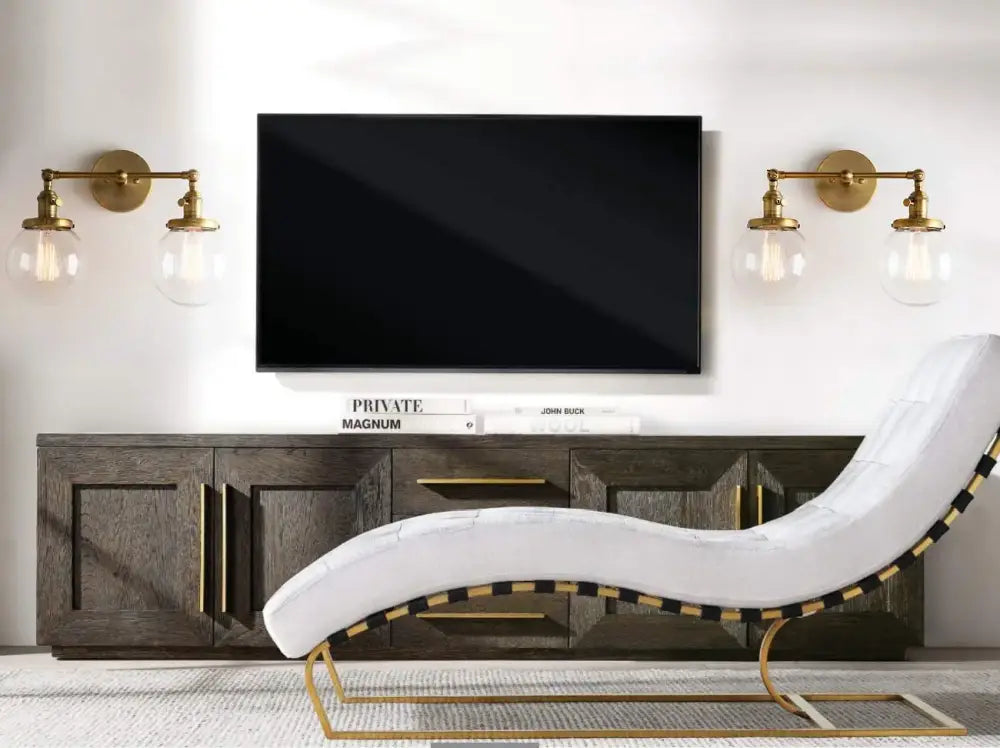 White upholstered chaise lounge with gold-tone metal frame and black and gold striped trim near modern vintage double ball heads globe wall sconce
