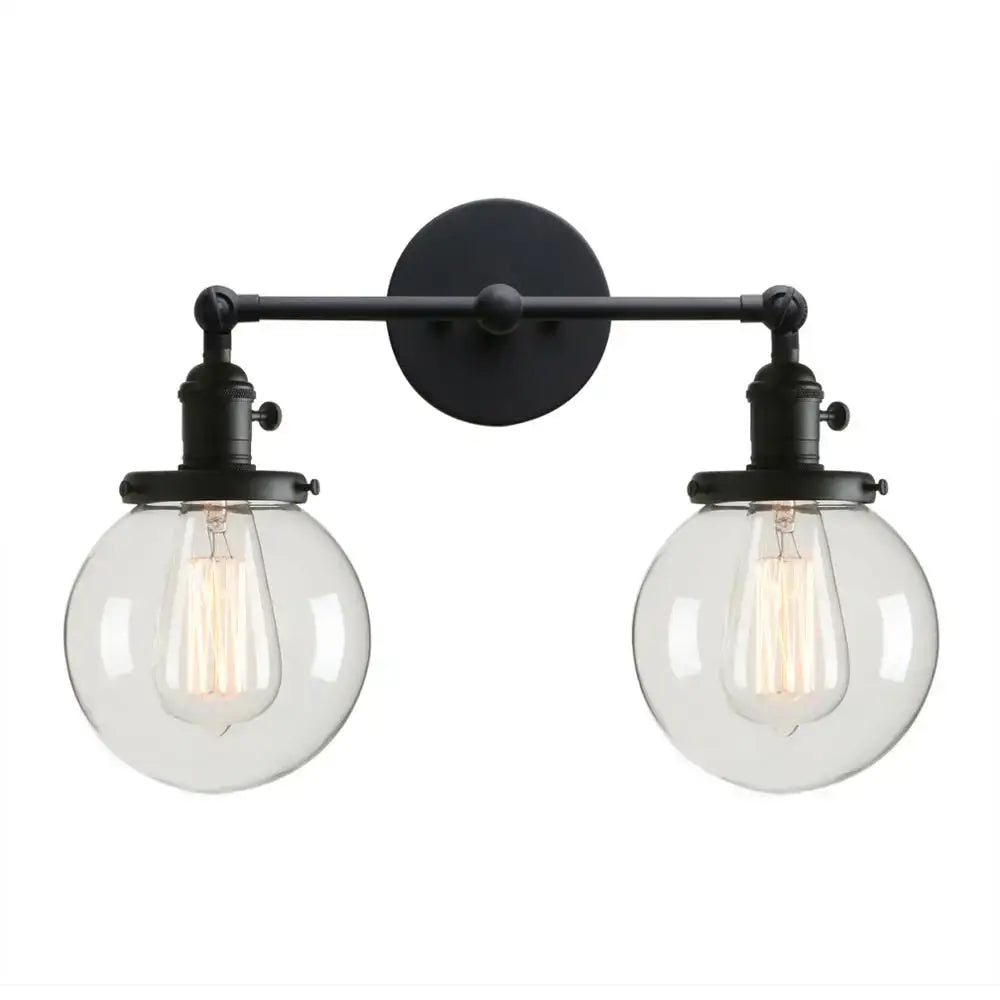 Black wrought iron wall sconce with double ball heads clear glass globes and exposed filament bulbs for bedroom use
