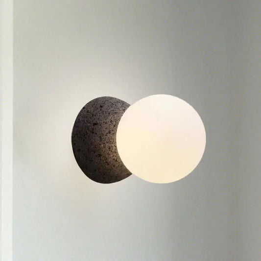 Modern wall lamp with dark volcanic stone bulb base and smooth white glass shade for stylish living room decor