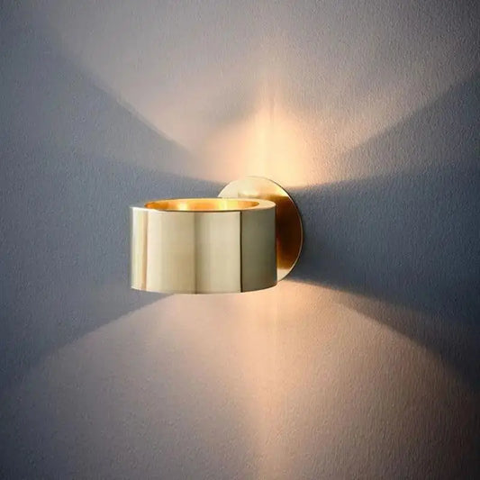Gold-toned modern wall lamp with sleek segmented barrel design for stylish indoor lighting