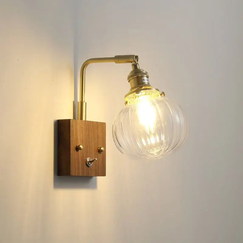 Brass-finished wall sconce with walnut copper wooden base and clear glass ribbed globe bulb for modern stair lighting
