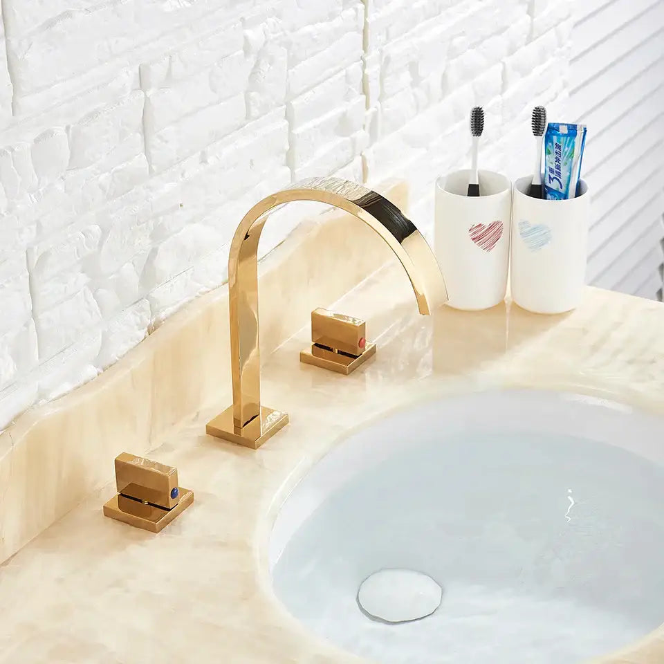 Modern waterfall dual handle gold basin faucet with a sleek curved spout and square base plates by decorbites dual handle gold