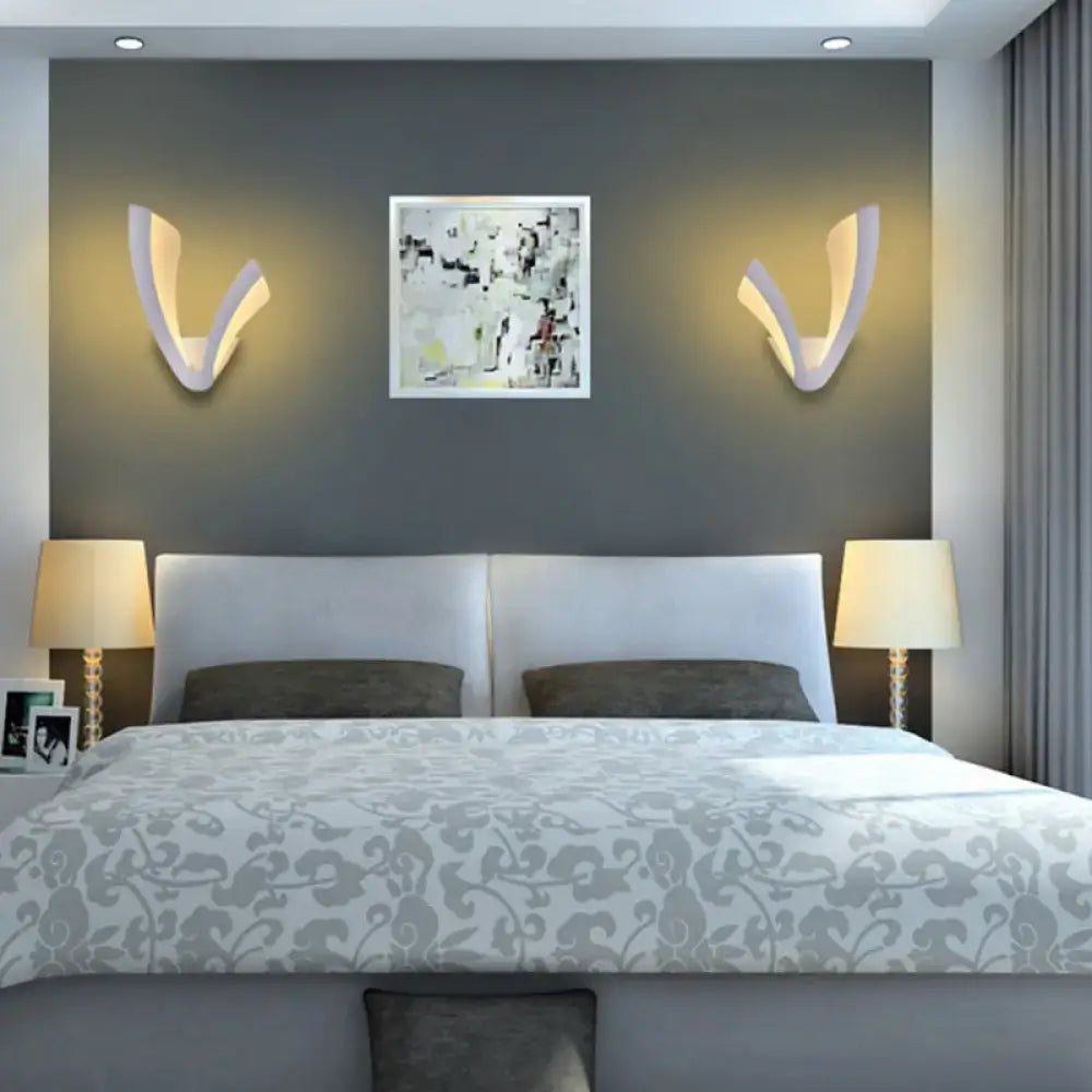 Modern white acrylic wall lamp with v-shaped design and matte finish providing warm ambient lighting for bedroom