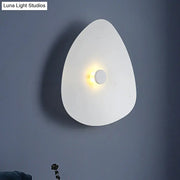 Modern white acrylic flaky sconce light with a sleek teardrop shape and warm central light for bedroom walls