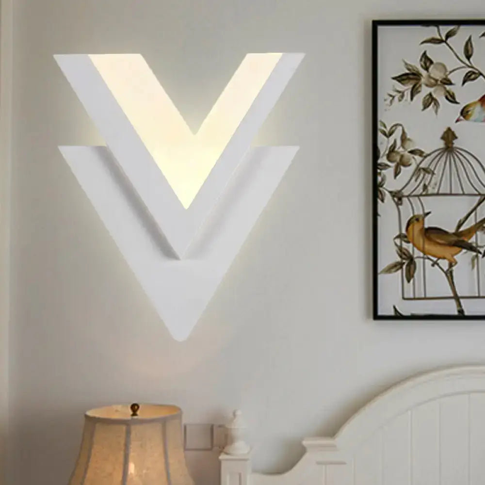 Modern white acrylic sconce light with v-shaped layered geometric design providing warm white glow for bedroom