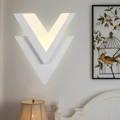 Modern white acrylic sconce light with v-shaped layered geometric design providing warm white glow for bedroom