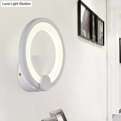 Modern white acrylic sconce light featuring a circular glowing ring and sleek minimalist design for bedroom walls