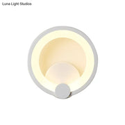 Modern white acrylic sconce light with circular concentric ring design emitting warm ambient light for bedroom use