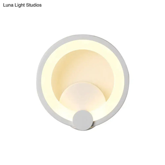Modern white acrylic sconce light with circular concentric ring design emitting warm ambient light for bedroom use