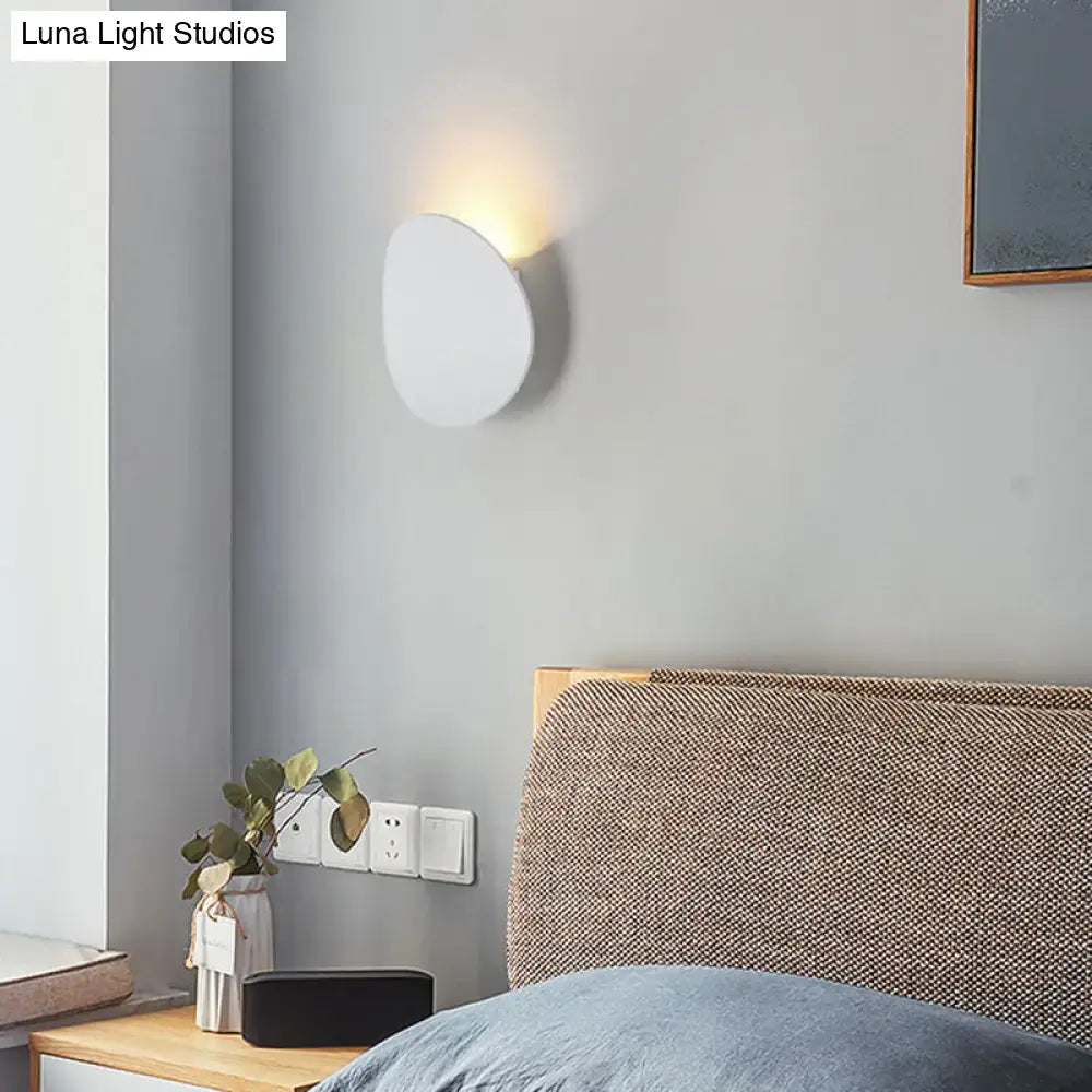 Modern style wall sconce in white and black with sleek oval design emitting warm led light for bedroom use
