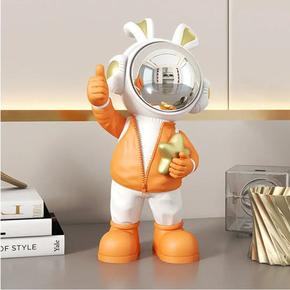Modern white and blue astronaut resin sculpture featuring an orange astronaut resin with bunny ears holding a golden star