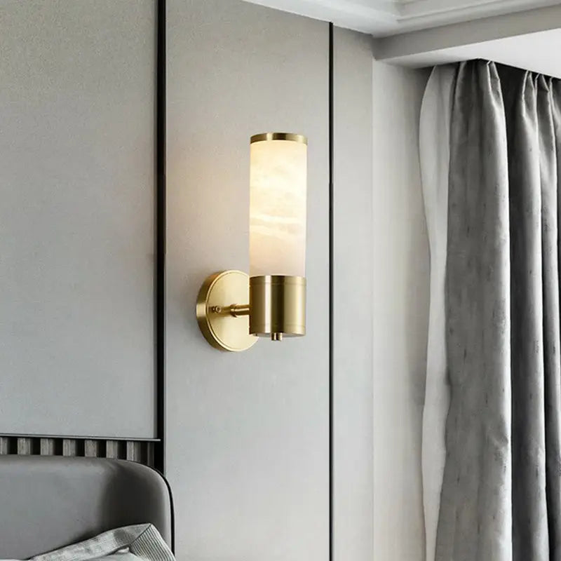 Modern white and brass pillar shaped sconce light with gold-toned bedside wall lamp and frosted glass shade