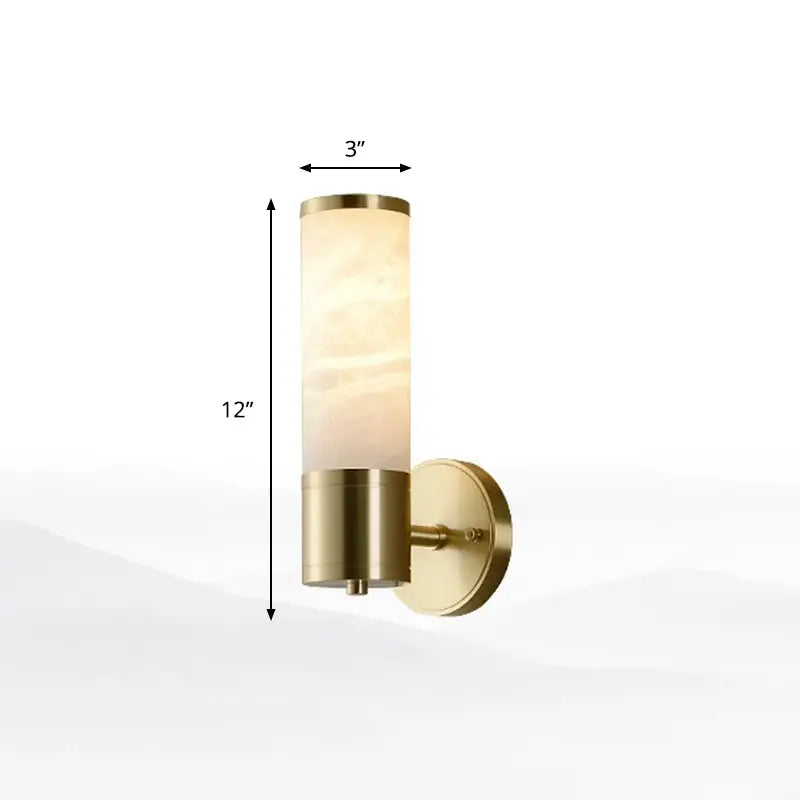 A sleek 12-inch tall modern white and brass pillar shaped sconce light with brushed brass finish and glass shade