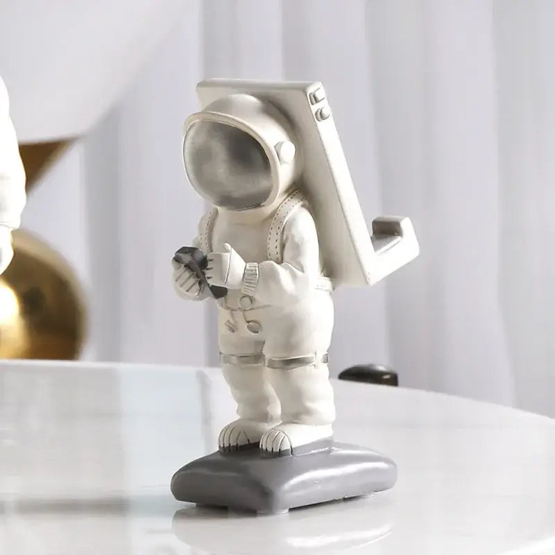 Modern white and gold astronaut phone holder figurine with metallic silver helmet and backpack on gray base decorbites astronaut phone decor