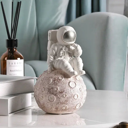 Modern white and gold astronaut phone holder figurine sitting atop a textured cratered moonbase for decorbites astronaut phone use