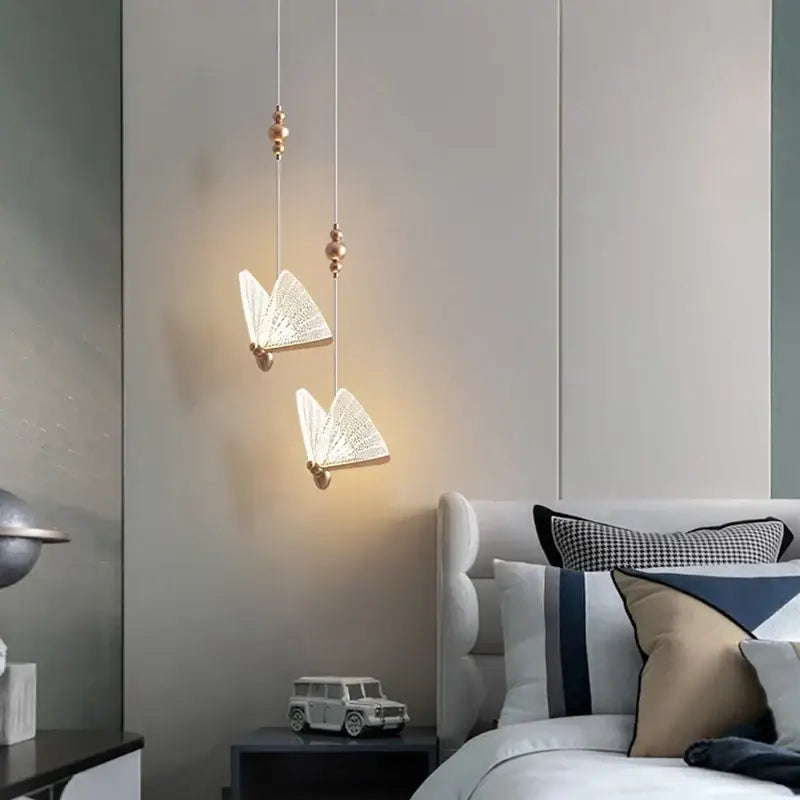 Two elegant white and gold decorbites butterfly pendant lights hang from the ceiling for modern bedroom decor
