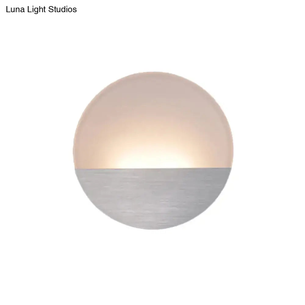 Modern white and silver led sconce light with frosted glass and brushed metal emitting warm bedroom glow
