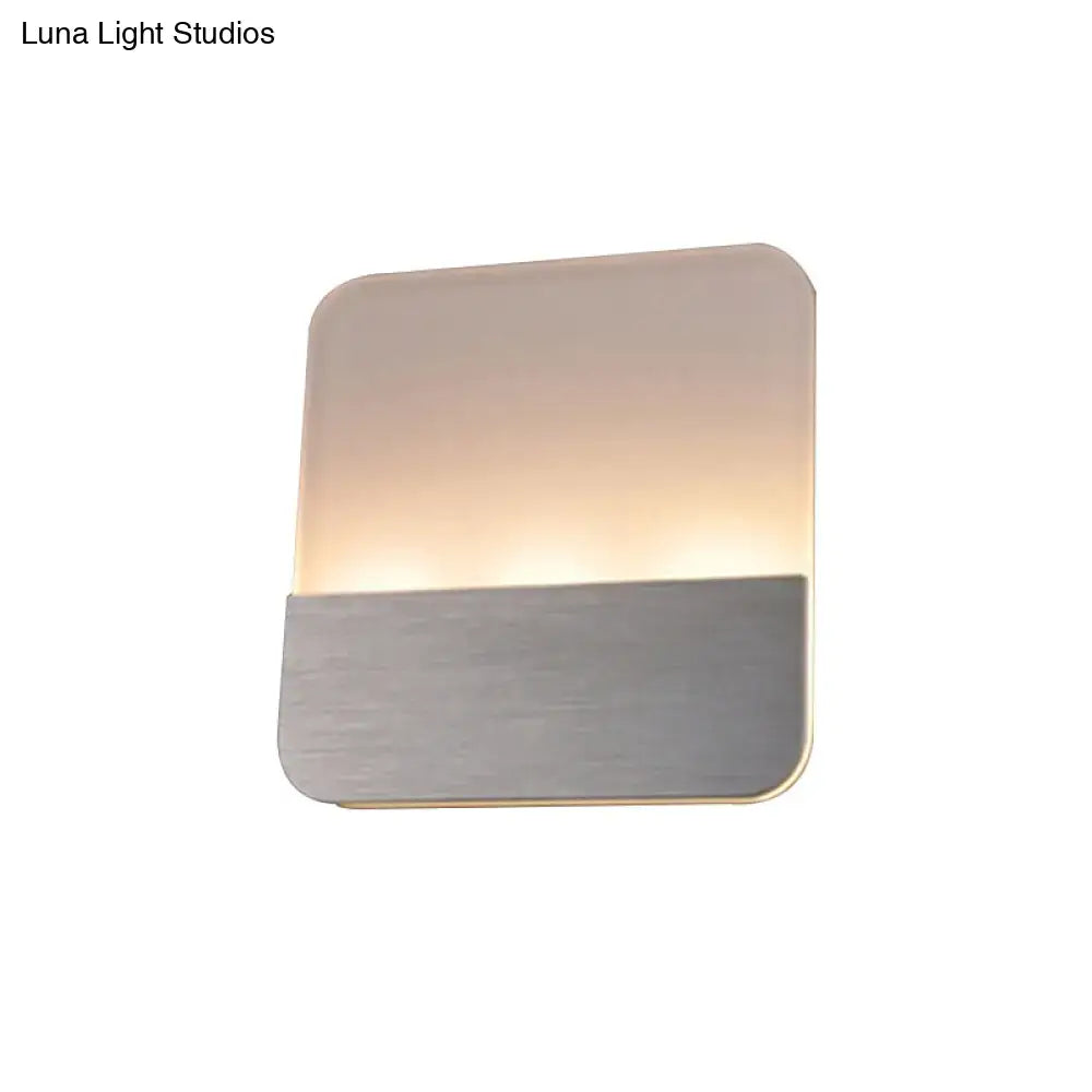 Modern white and silver led sconce light with frosted glass top and brushed metal base emitting warm glow for bedroom