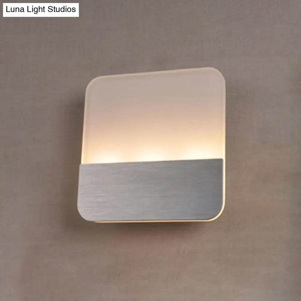 Modern white and silver led sconce light with frosted glass top and brushed metal base emitting warm glow for bedroom