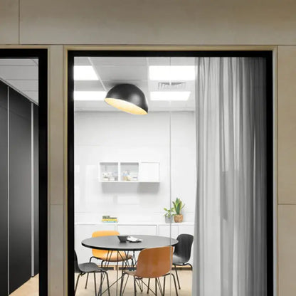 Black dome-shaped pendant ceiling light with warm yellow glow part of a modern white and wood duo ceiling light set