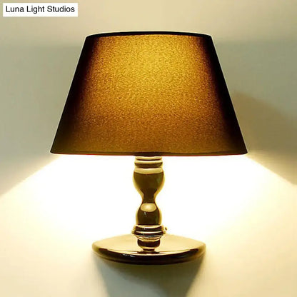 Gold-finished table lamp with textured warm amber shade complementing modern white black cone ceramic wall sconce bedroom light
