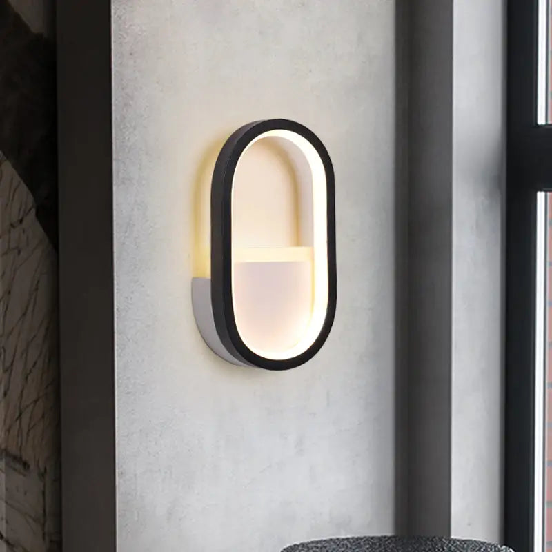 Modern white and black ellipse led wall lamp with sleek black frame and warm white illuminated interior for bedroom use