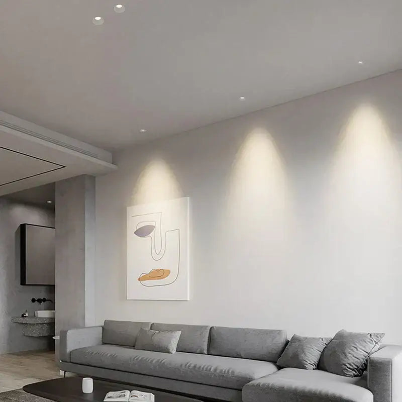 Modern white and black recessed downlight spotlights installed above gray sofa with beige and brown abstract wall art decorbites 12w