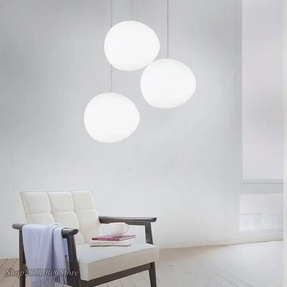 Three minimalist white spherical glass pendant lights cascade from the ceiling for modern dining room lighting