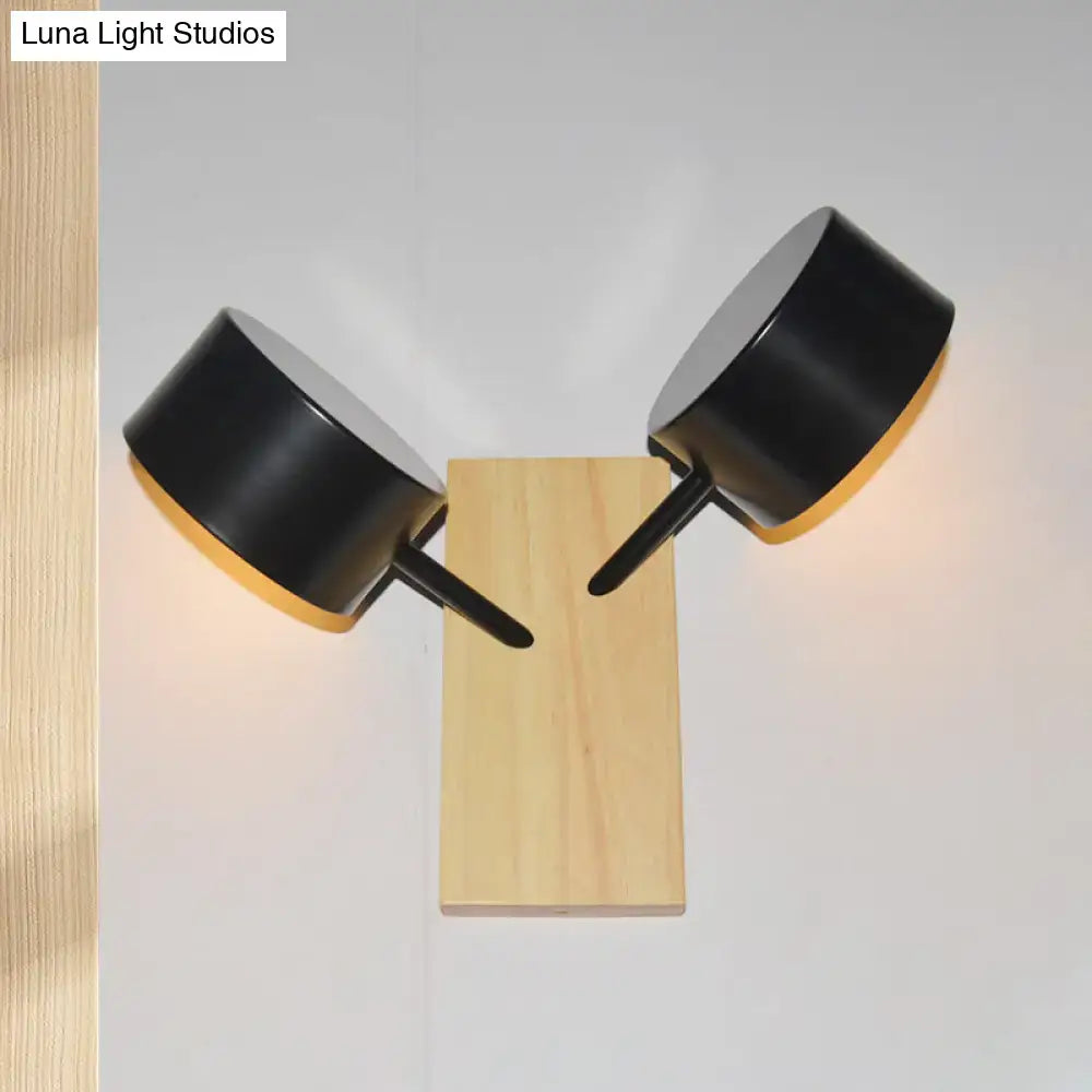 Black matte double drum wall sconce with two cylindrical heads on light wood base fixture height for 220v-240v use