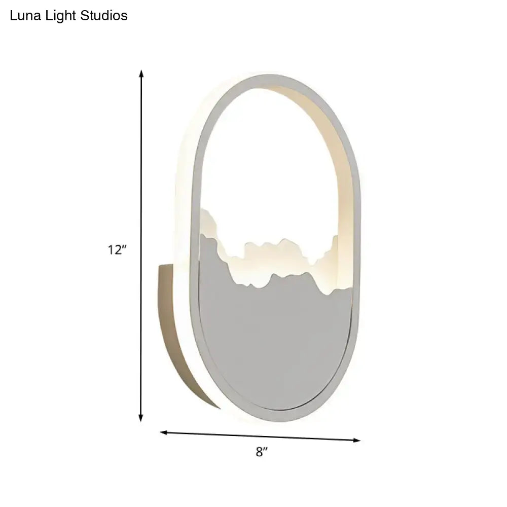 Modern white cracked design oval sconce lamp with sleek gray and white finish and illuminated mountain silhouette for stairway lighting