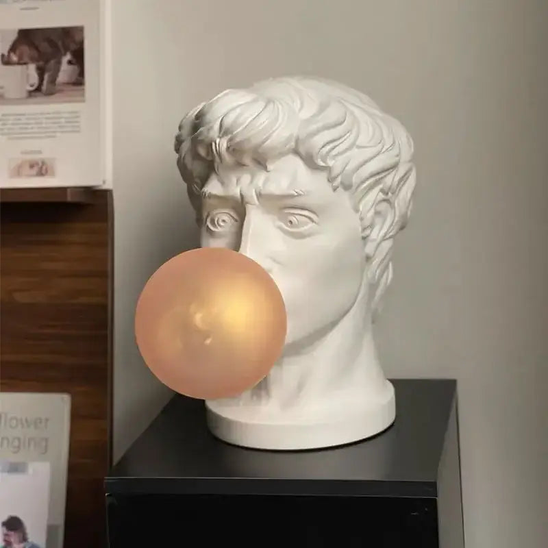 Modern white david sculpture table lamp featuring a marble-style bust blowing a peach bubblegum bubble for decorbites decorbites david sculpture table