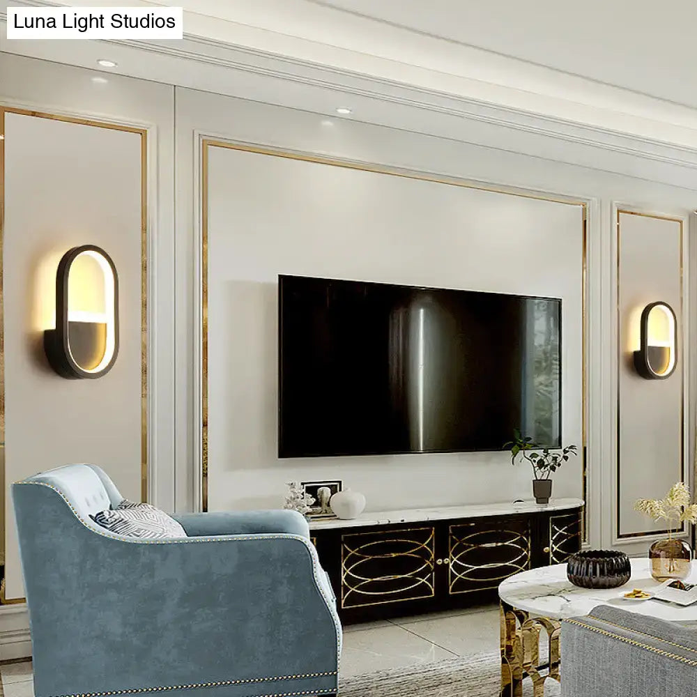 Modern white elliptical led wall lamp bedroom sconce shown beside a sleek black flat-screen television on white wall with gold panels