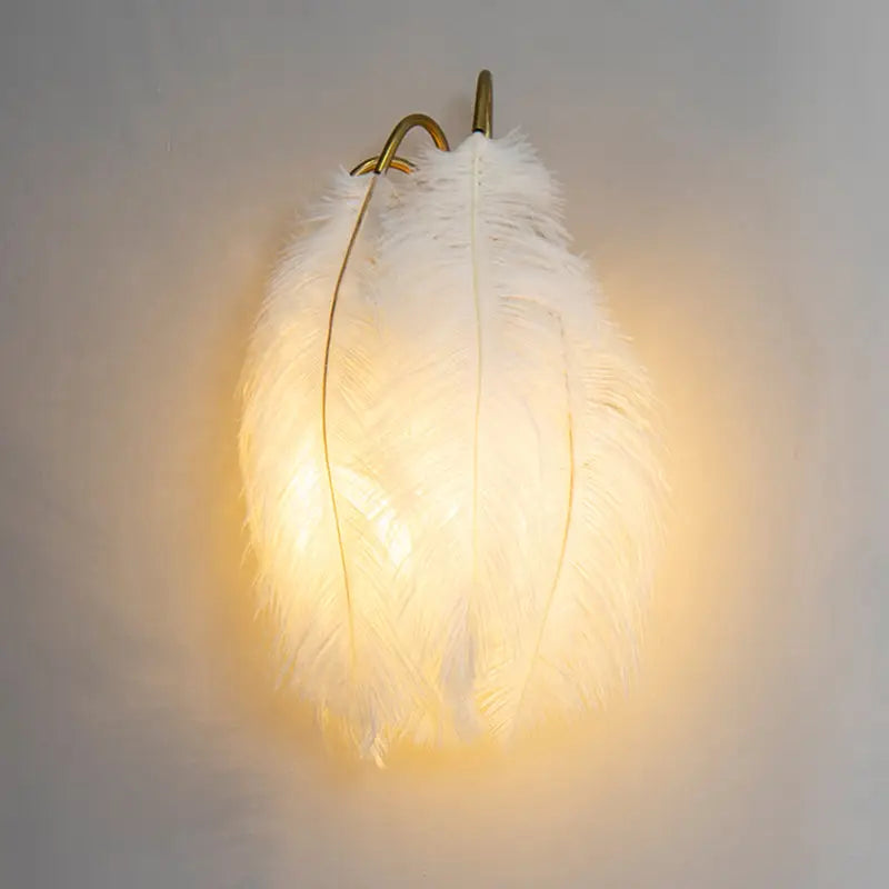 Modern white feather metal wall sconce with gold-toned hook for bedroom lighting in a modern metal wall design