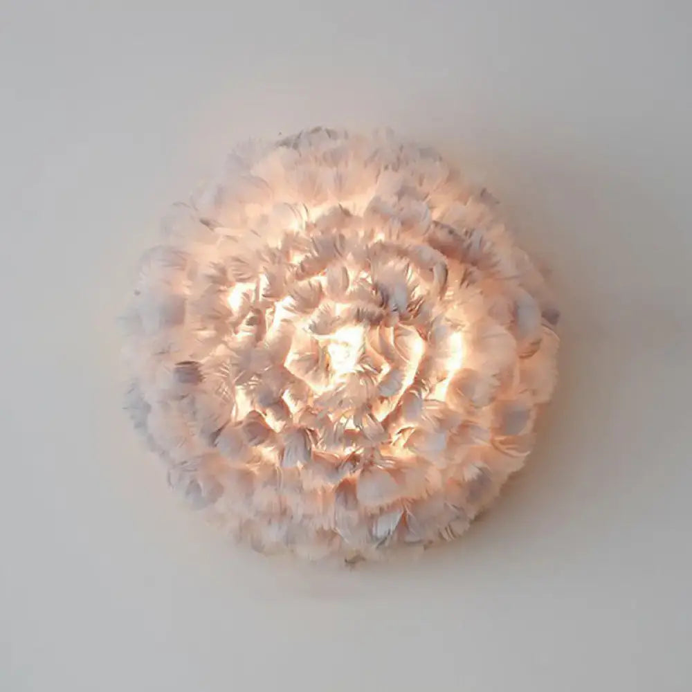 Modern white feather wall sconce featuring a soft circular design with layered feathers radiating a warm glow