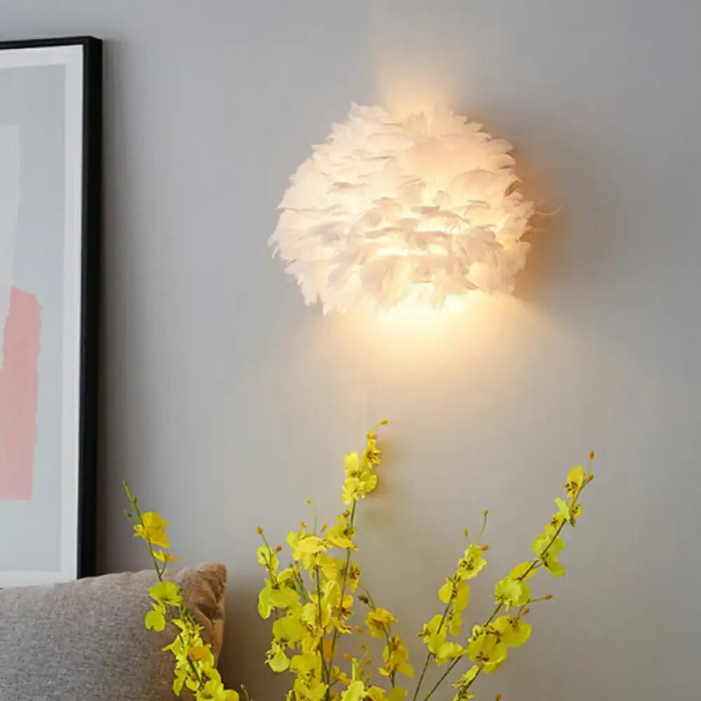 Modern white feather wall sconce with soft white feathers emitting a warm glow for bedroom lighting