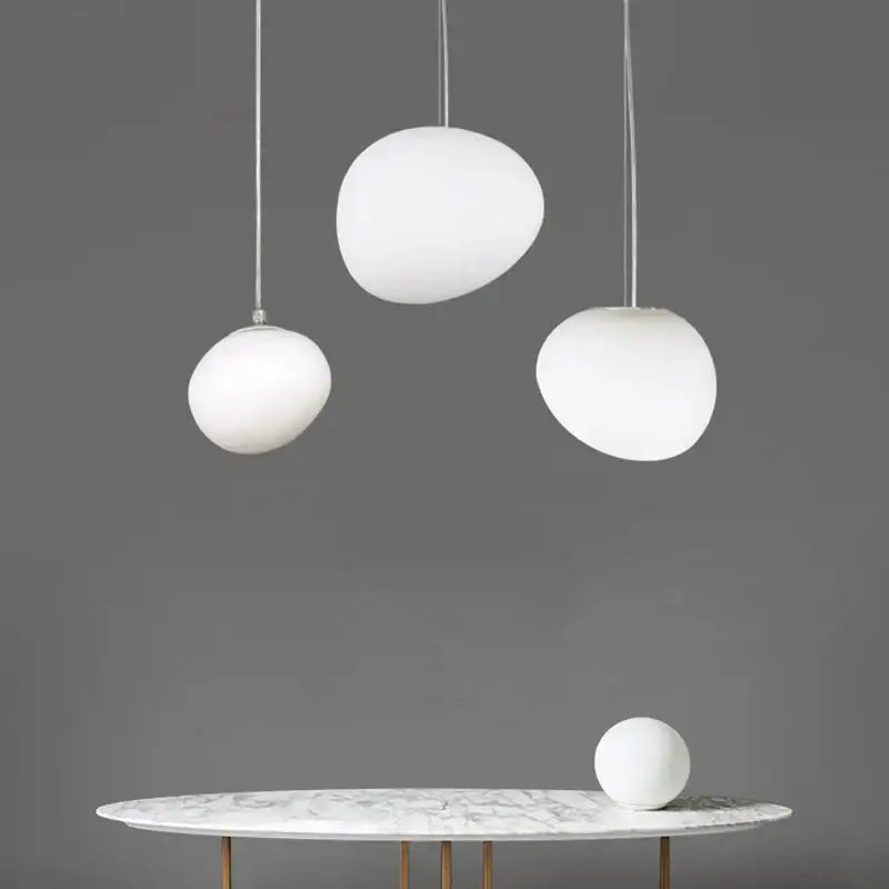 Three modern white frosted glass ball led pendant lights hang above a marble table for dining room decorbites pendant light