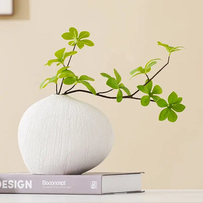 Modern white geometric stripes ceramic vase with textured finish holding a branch with vibrant green leaves decorbites geometric stripes ceramic decor