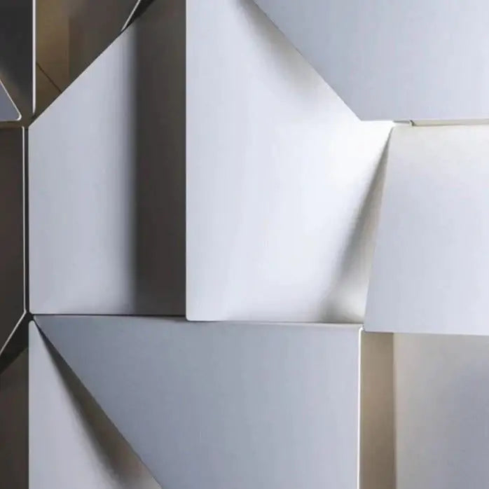 Modern white geometric wall lamp featuring interlocking white and metallic silver triangular facets illuminated art
