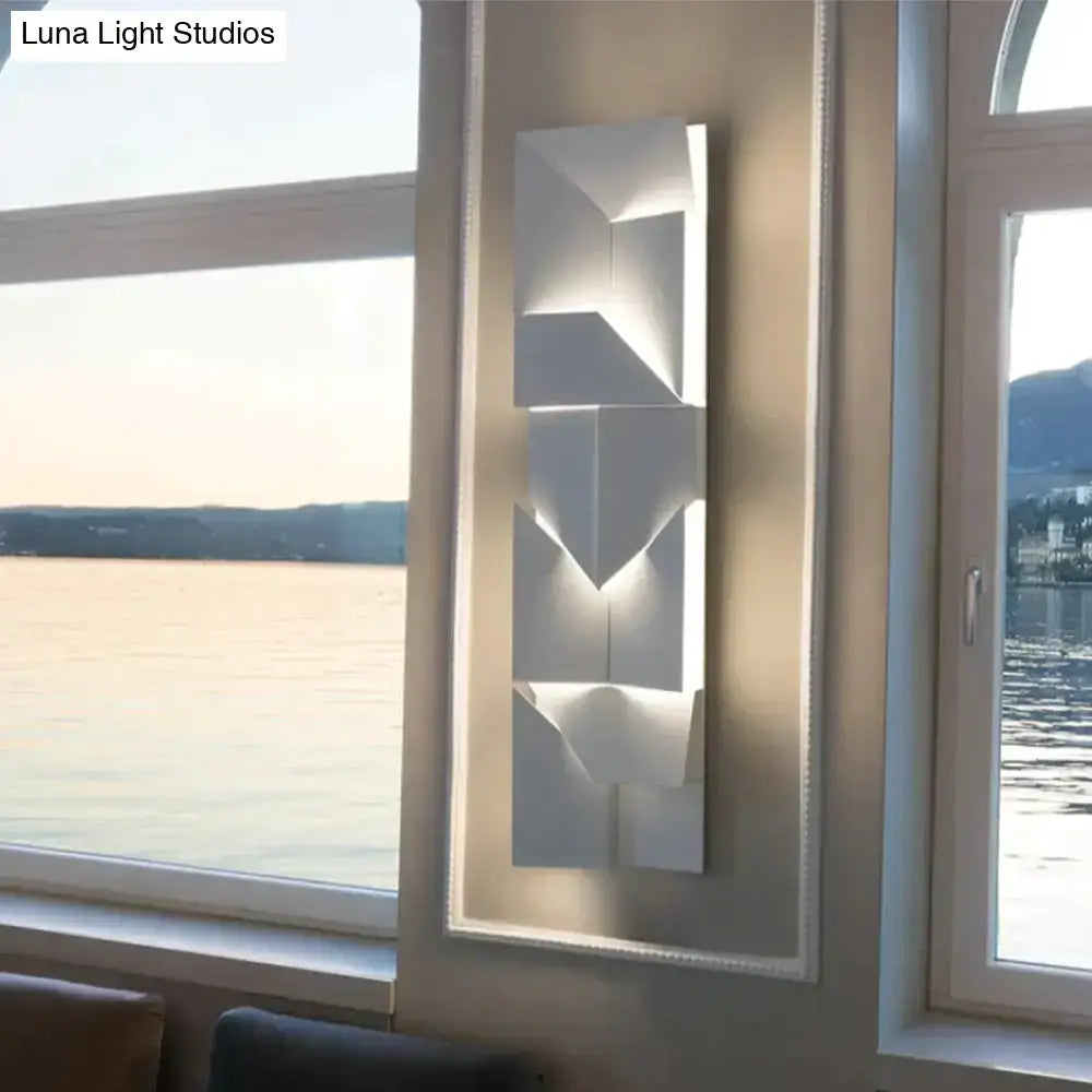 Modern white geometric wall lamp with layered angular facets casting soft light ideal for living room illumination