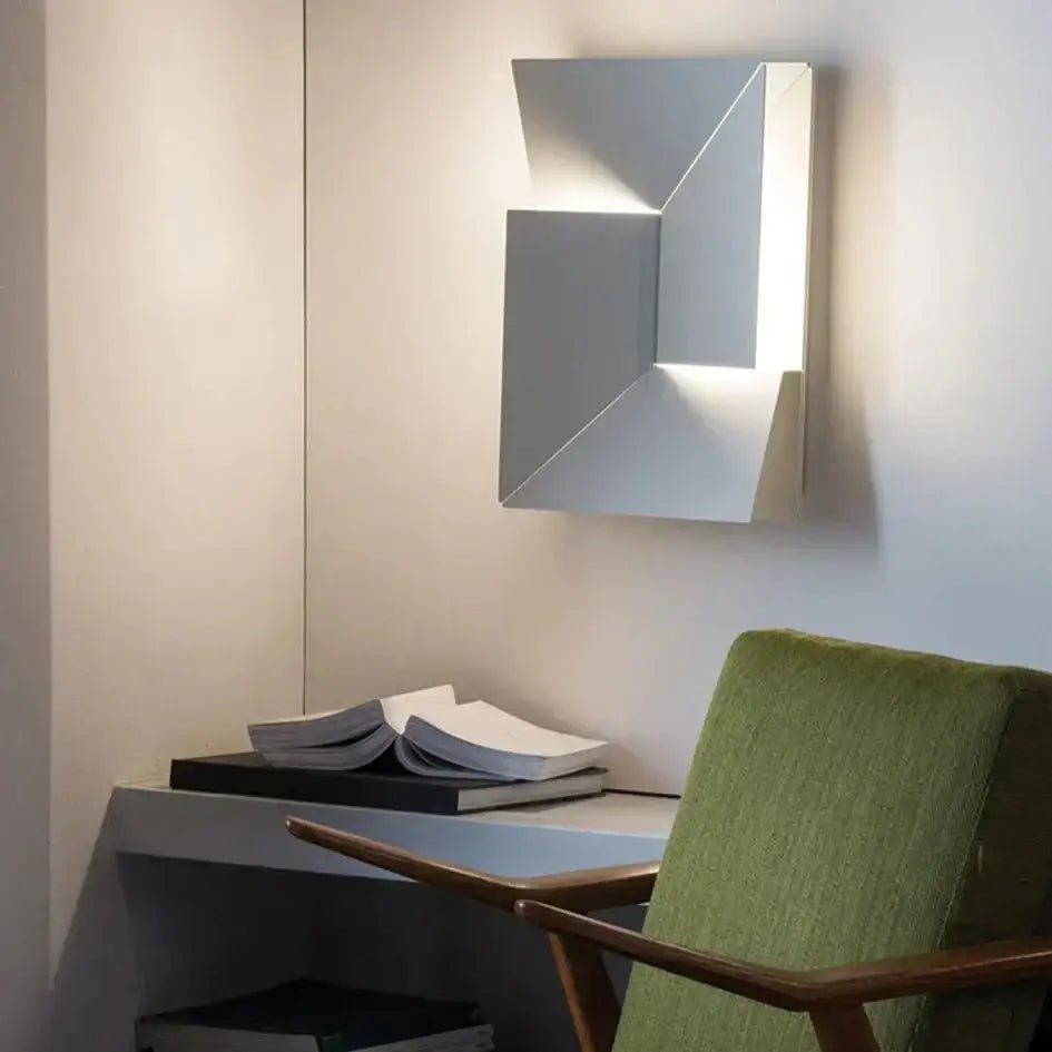 Modern white geometric wall lamp with sleek silver metallic finish and angular folded design for illuminated living room art