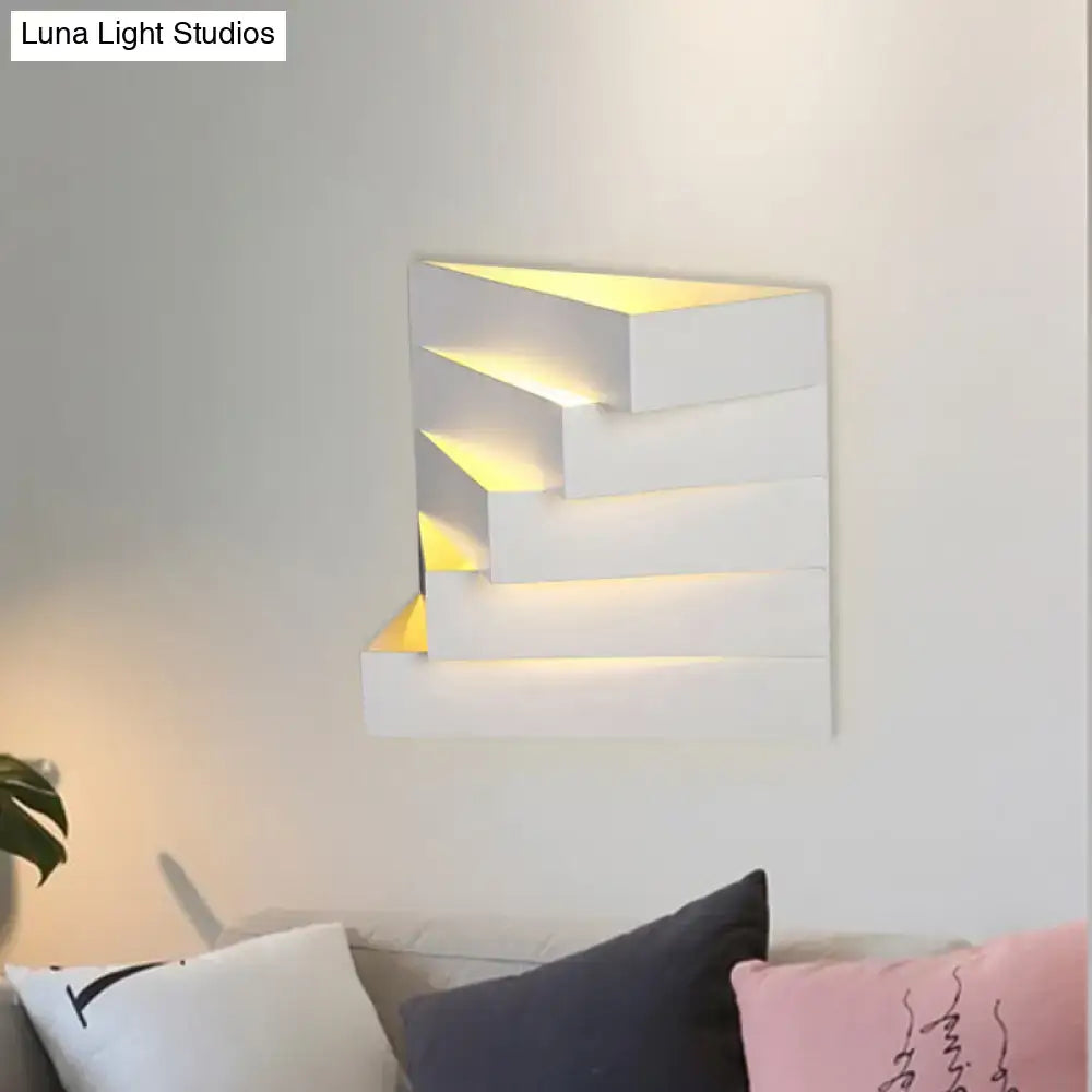 Modern white geometric wall mounted lighting sconce with layered stepped design and warm yellow backlighting