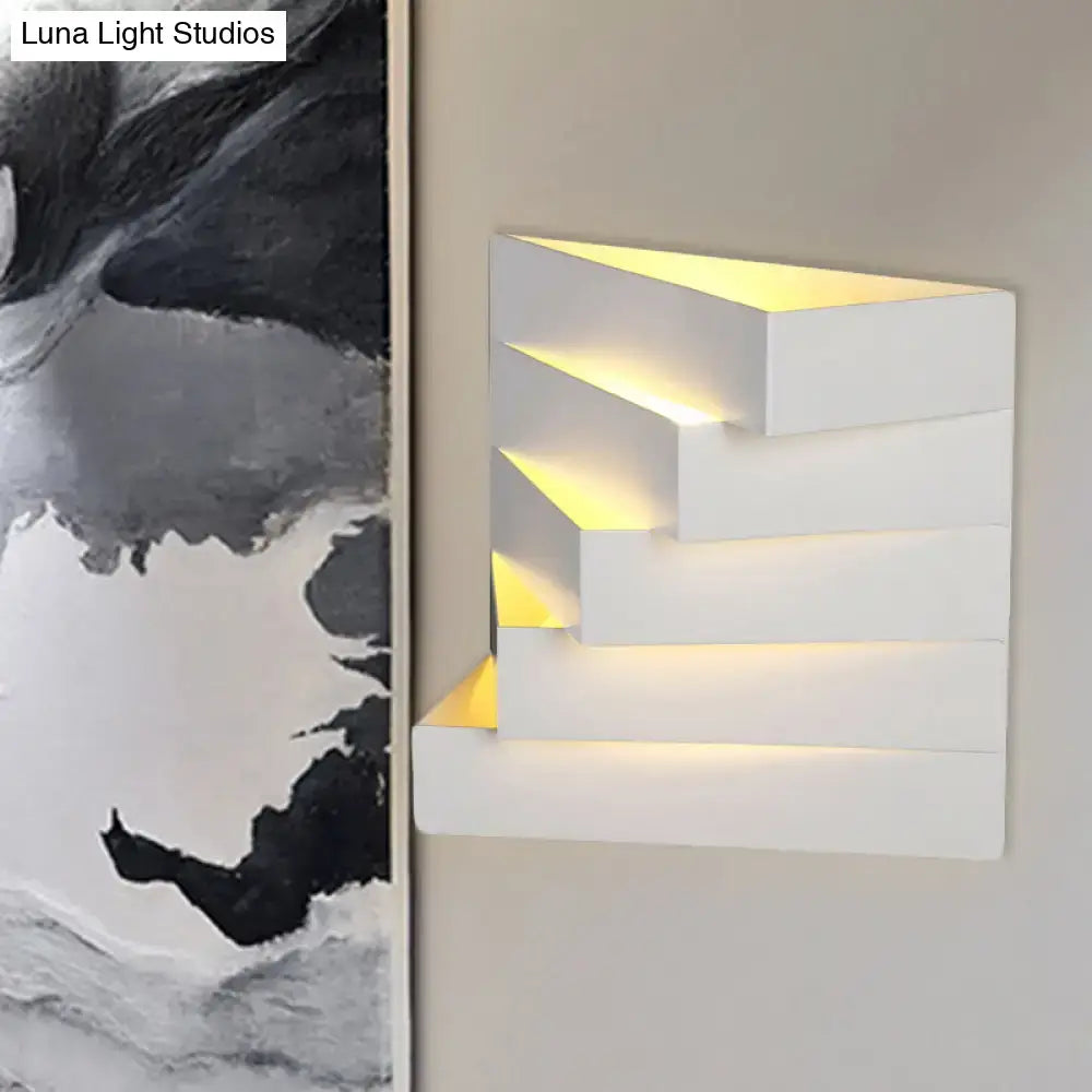 Modern white stepped wall mounted lighting sconce with warm yellow backlighting for living room use