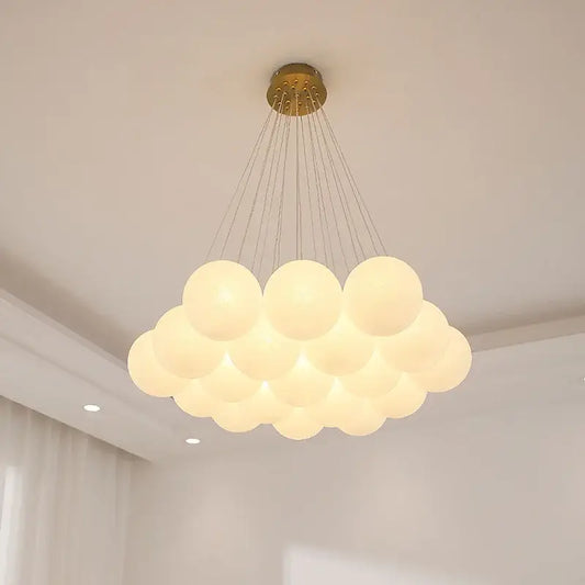 A modern white glass pendant light with frosted globes and a golden mount serves as a dining room focal point