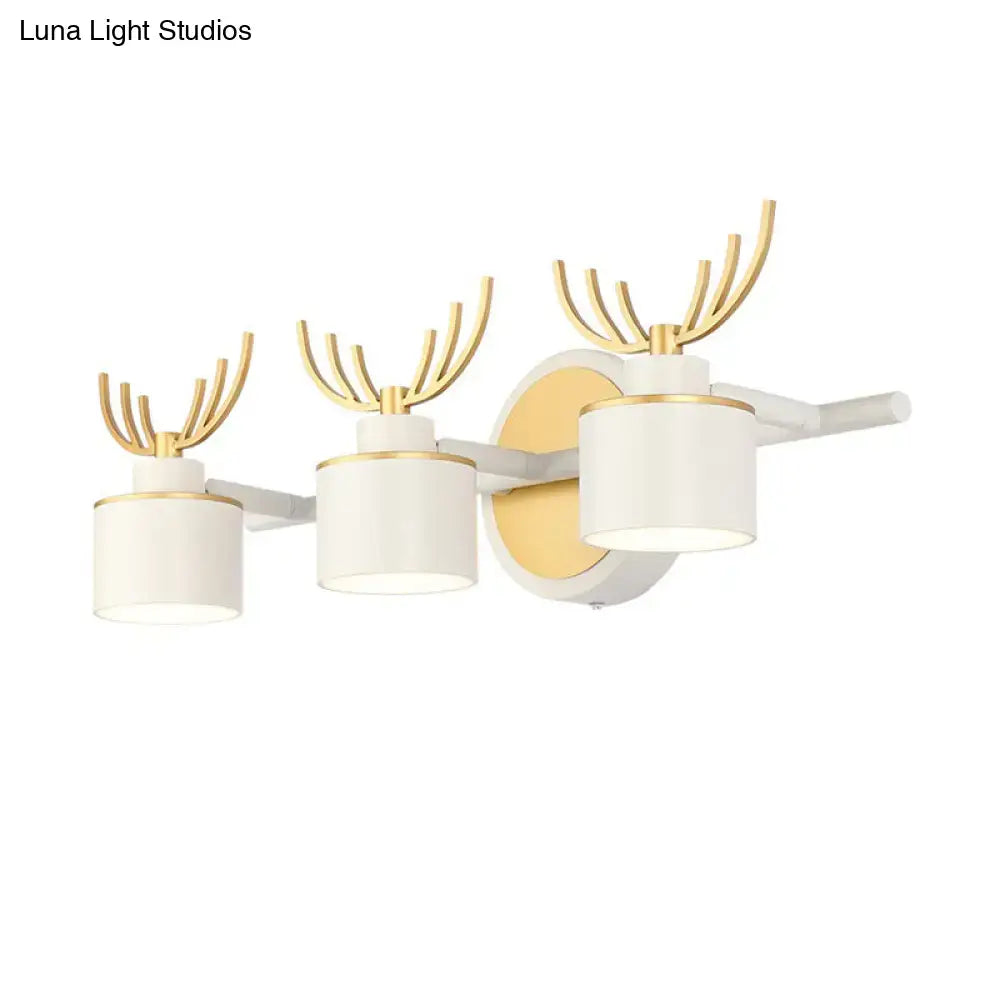 Modern white and gold antler wall light fixture with three cylindrical shades for bathroom vanity lighting