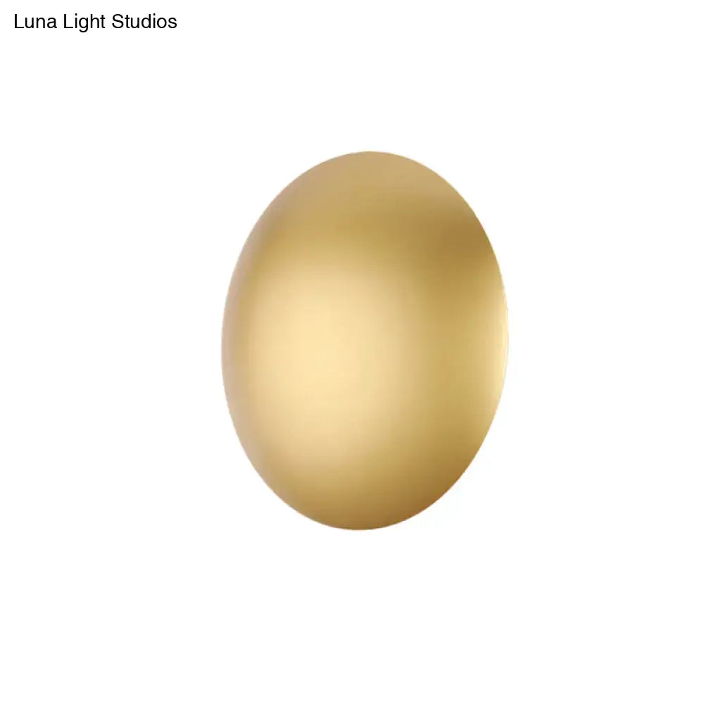 A smooth oval-shaped golden egg with matte finish featured in modern white gold warm white wall light for bedroom