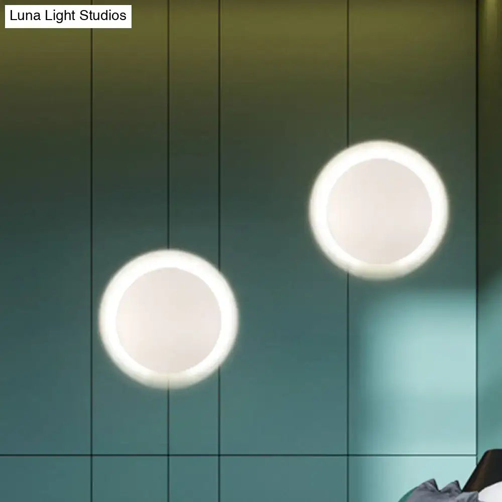 Two modern white gold circular led wall lights with warm white glowing rings against a dark green tiled wall